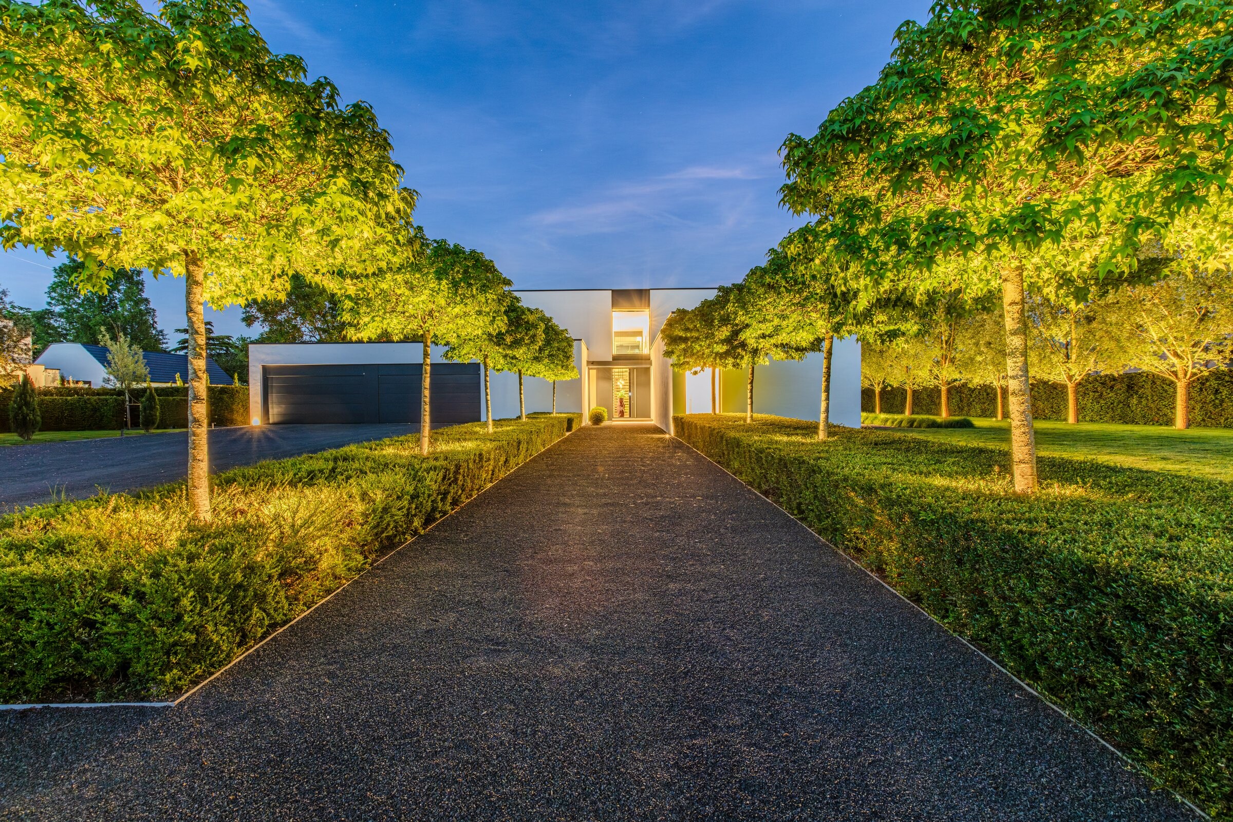 Beleuchtete Baumallee als Zuweg zur Villa bei Nacht