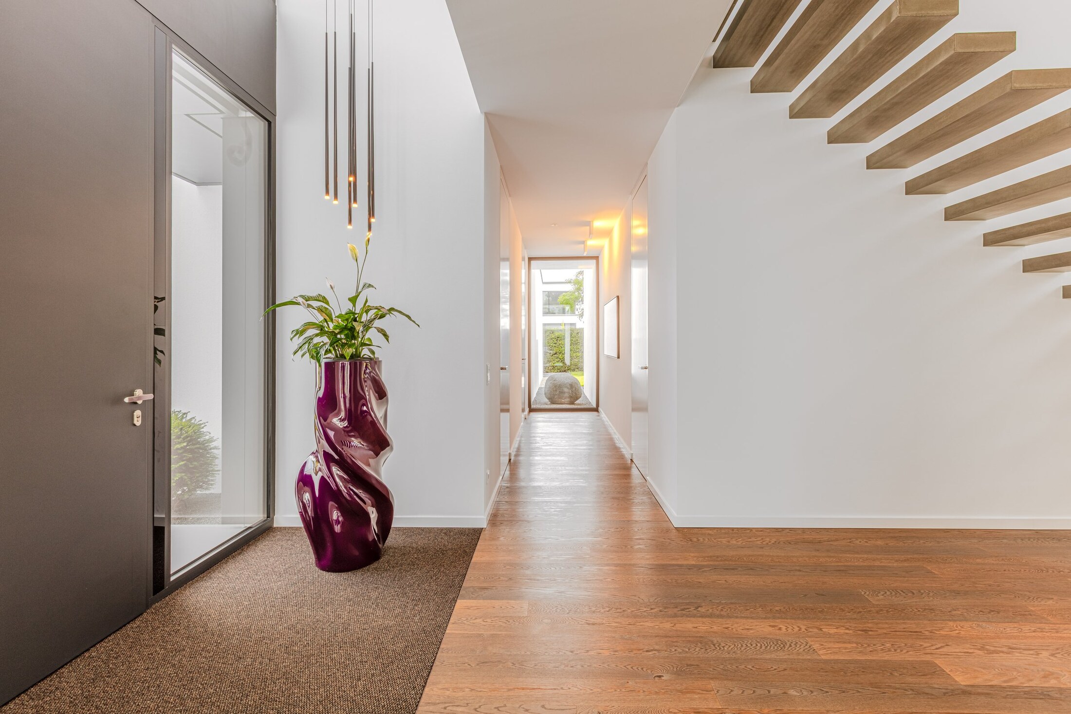 Blick durch die Haustür in den Eingangsbereich mit Eichenparkett und freitragender Treppe