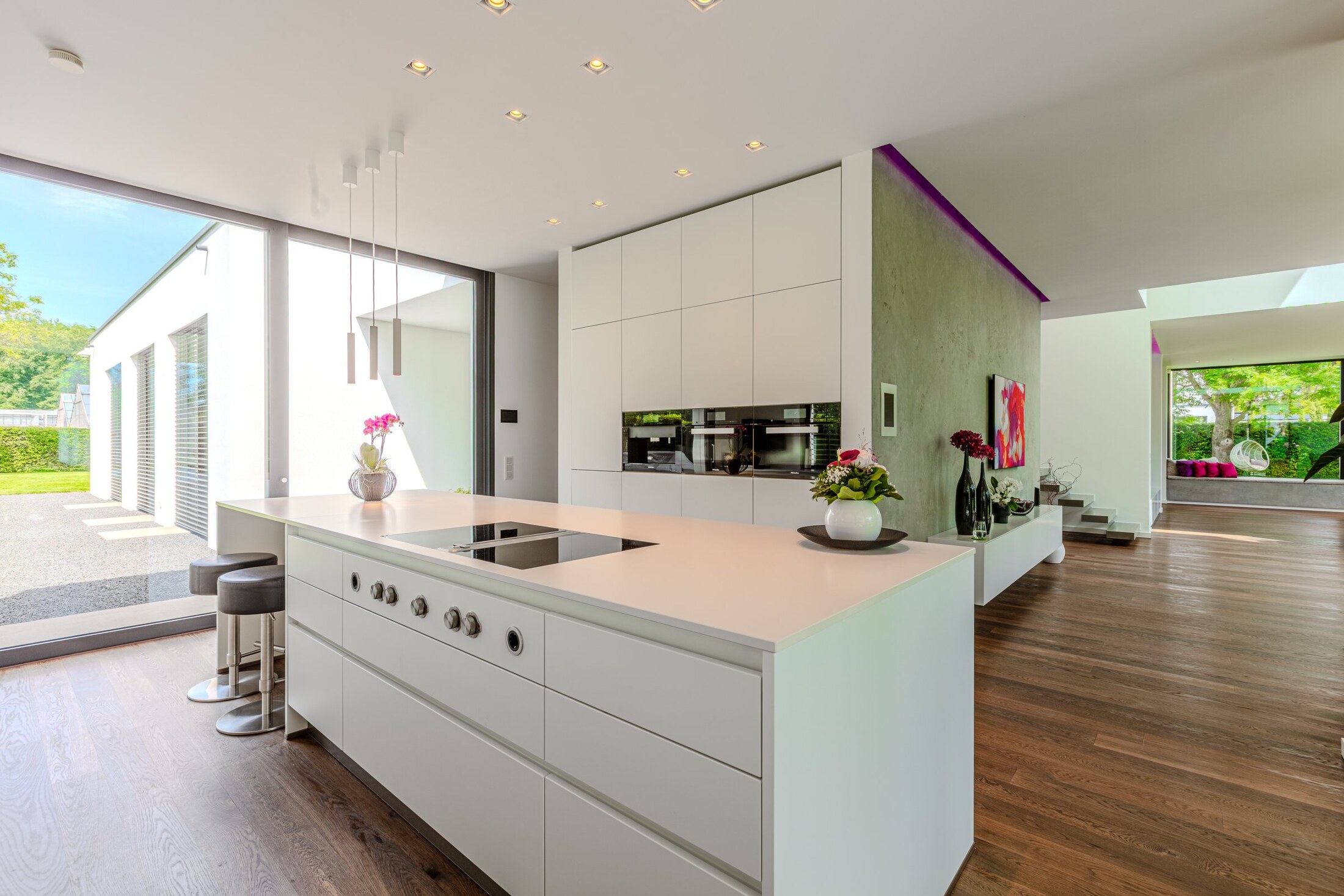 Küche mit BORA-Induktion, Mineralsteinplatte und Blick durch die Glasfront in den Garten
