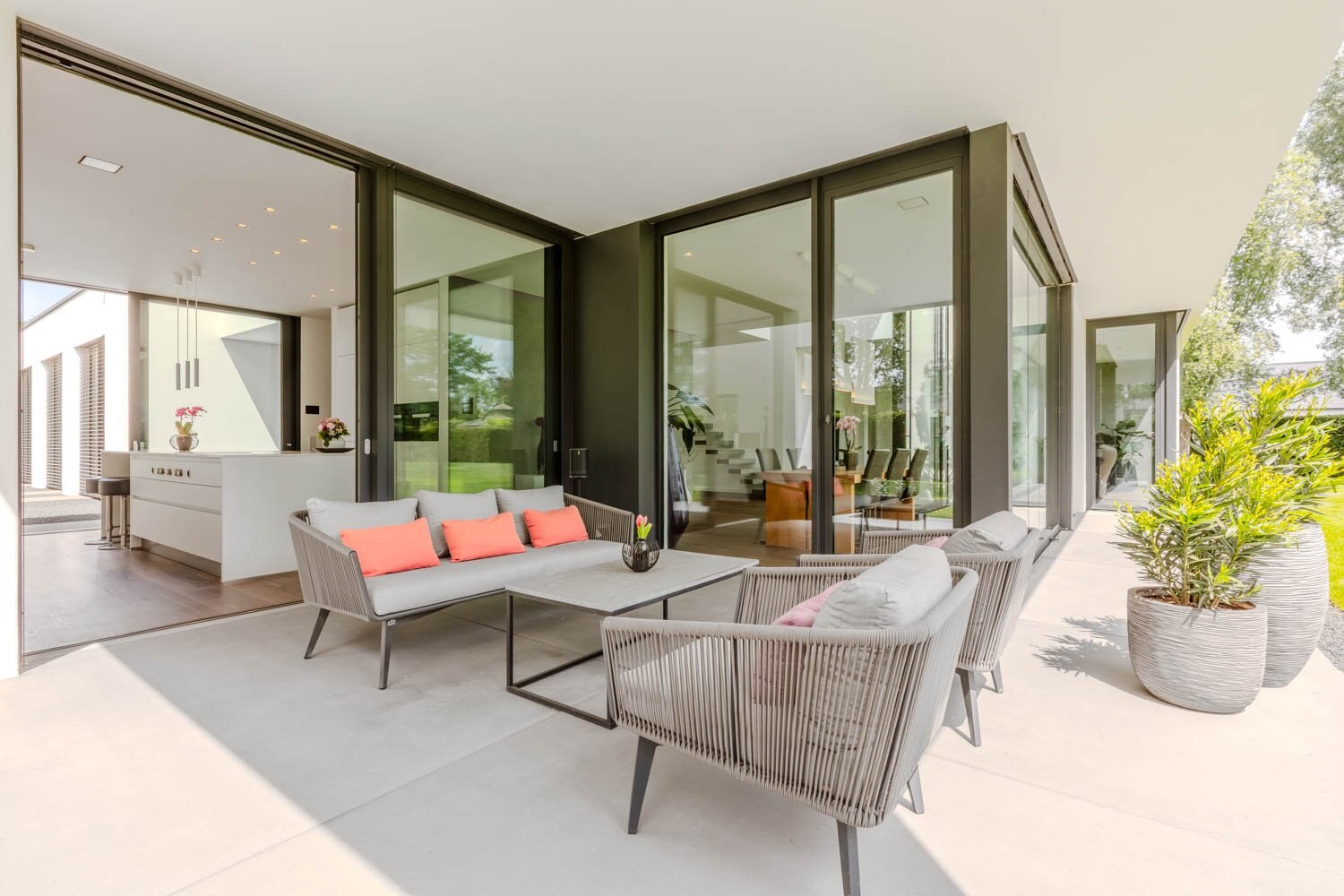 Überdachte Terrasse mit Lounge — Glasfronten zur Küche und zum Wohnbereich weit geöffnet